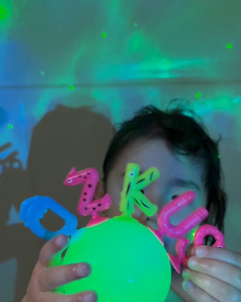 Child holding a glowing ball decorated with foam letters